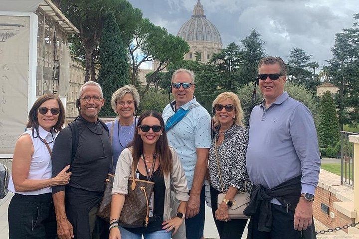 Visitors in a Vatican courtyard with the Basilica dome behind them