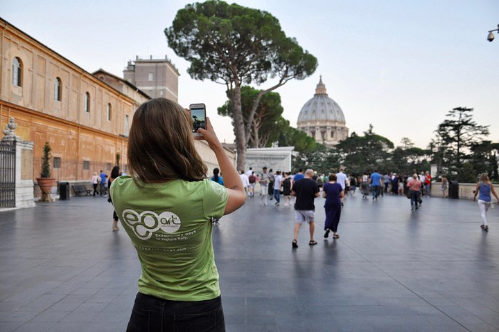 A visitor photographing the dome from a Vatican Museums courtyard