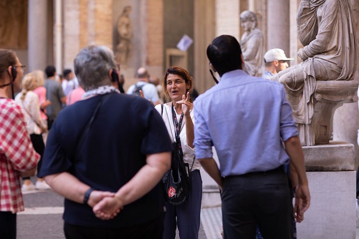 A guide speaking to visitors beside a marble sculpture