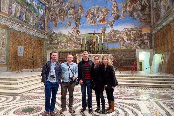 A group standing beneath The Last Judgment in the Sistine Chapel