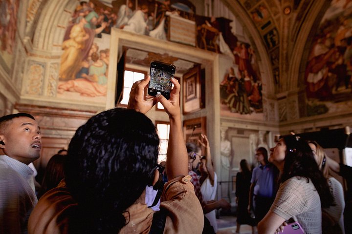 Visitors examining frescoes in a Vatican gallery