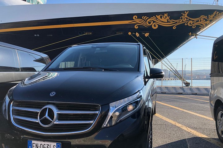 A passenger vehicle parked beside a cruise ship